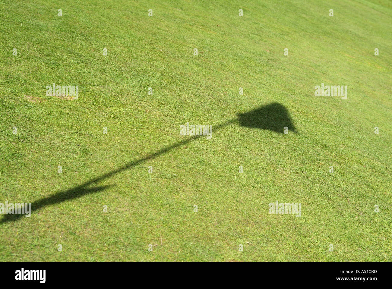 Shadow of a golf tee and flag on the green grass. England Stock Photo