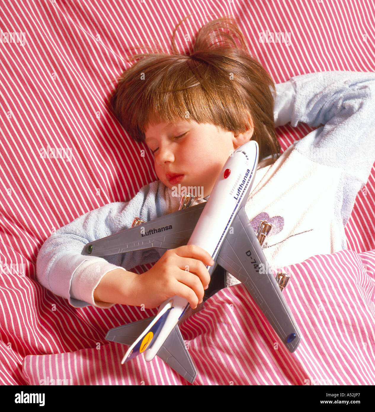 sleeping child holding airplane toy. Photo by Willy Matheisl Stock Photo