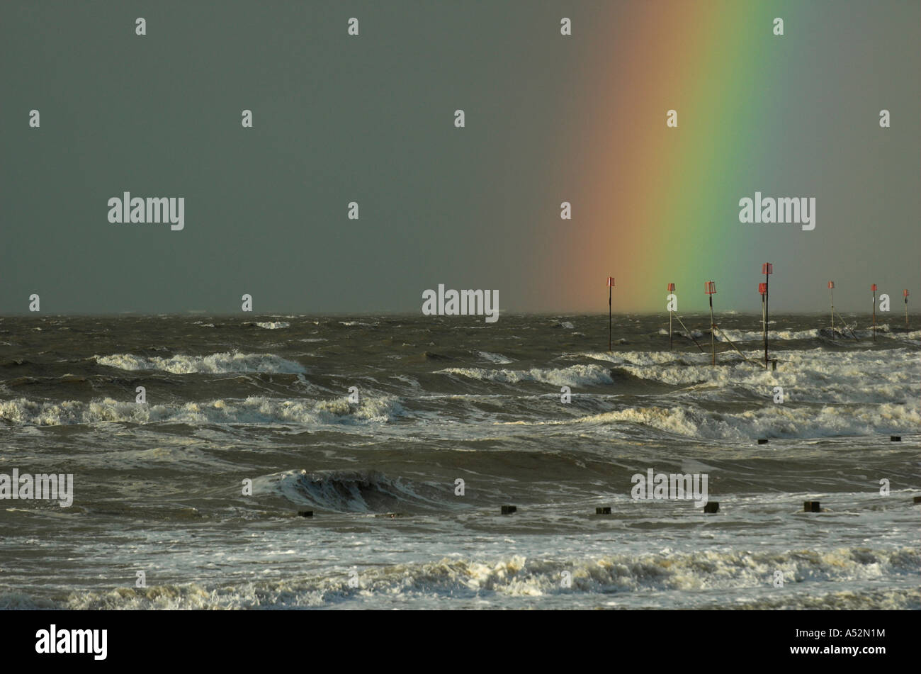 Rainbow over stormy sea and groynes Stock Photo - Alamy