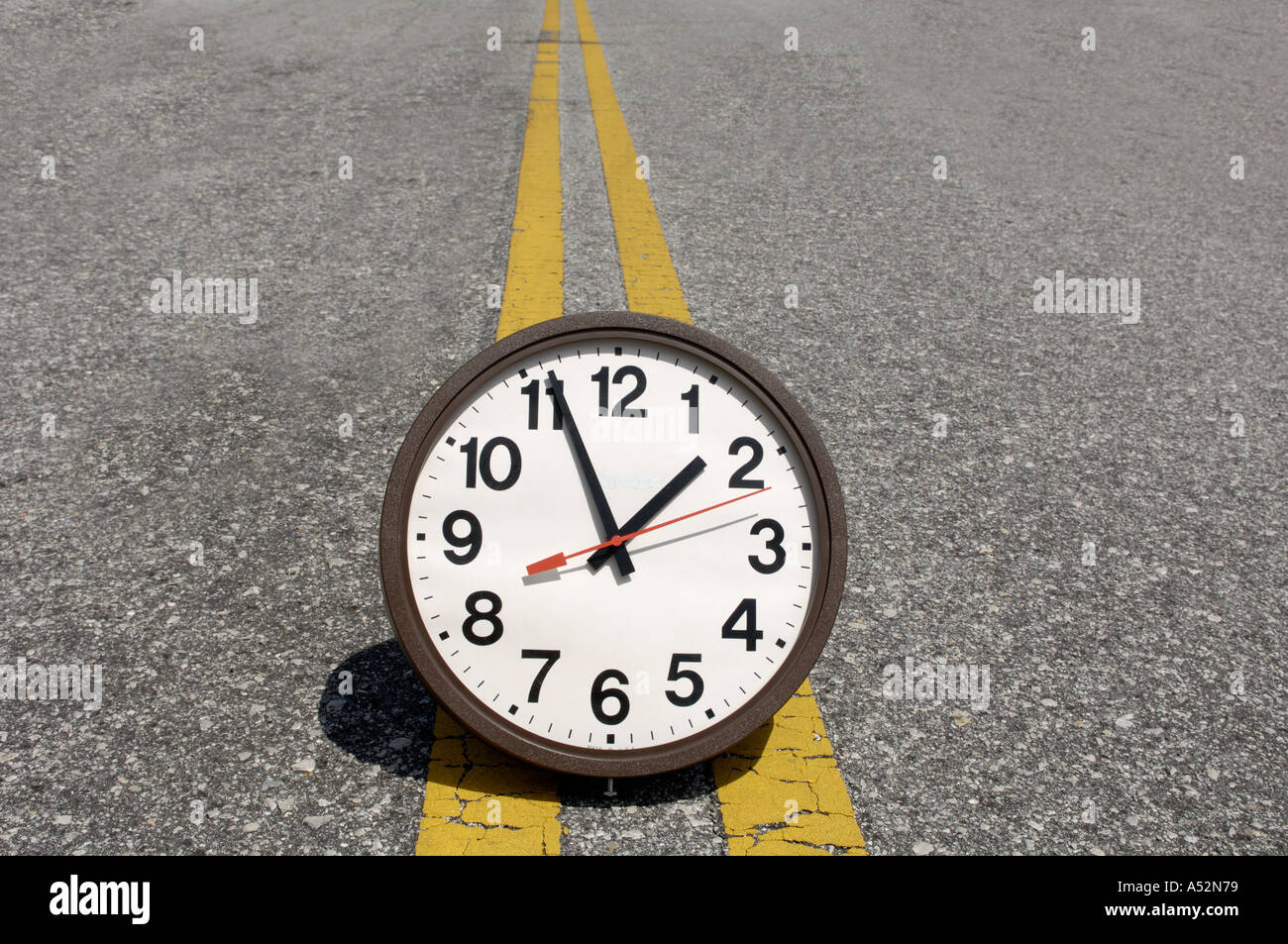 conceptual view of large clock on yellow stripes in roadway Stock Photo