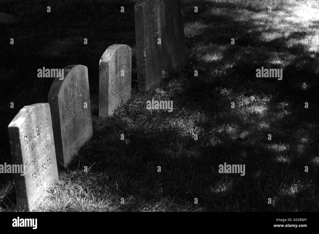 A black and white shot of some gravestones in a local cemetery in dramatic light. Space for copy. Camera:   Nikon D2x. Stock Photo