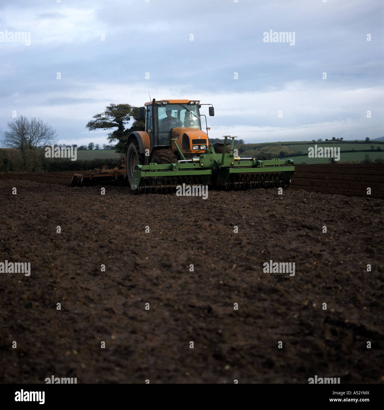Renault tractor with furrow press in front and harrow and crumbler behind preparing seedbed Stock Photo