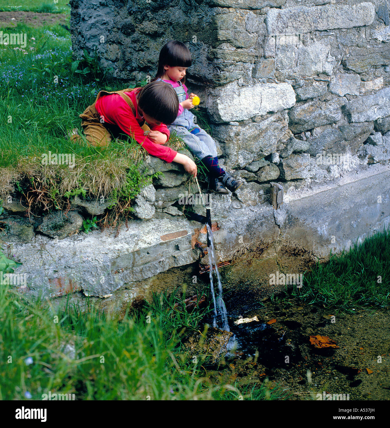children at play with water flowing from a outside well , Bavaria, Germany,.  Photo by Willy Matheisl Stock Photo