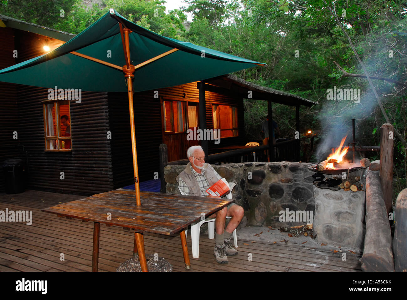 Grandpa reading a book next to the fire, Lekgalameetse Nature Reserve, Limpopo Province, South Africa Stock Photo