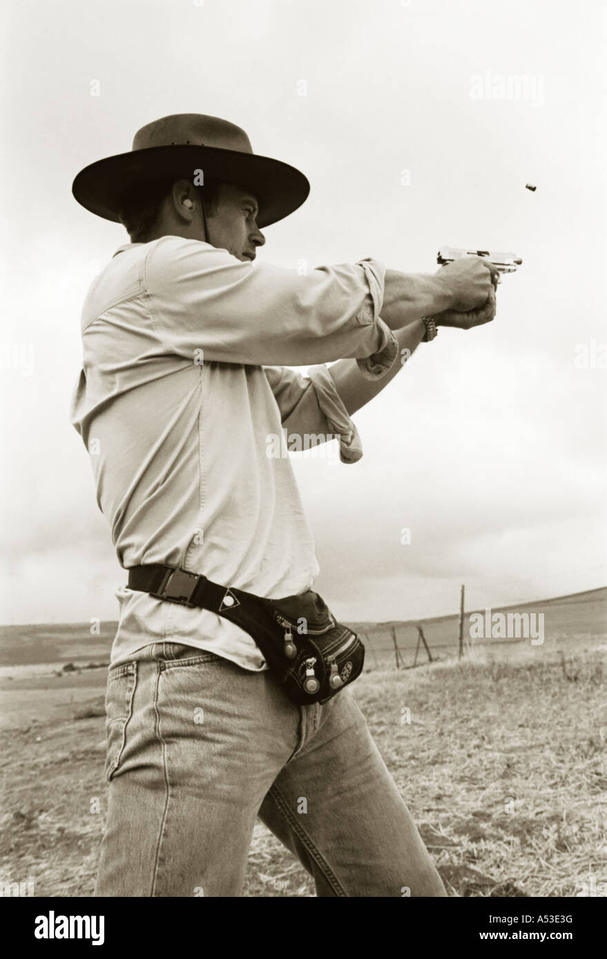 Tinted black and white portrait of man firing gun. Stock Photo