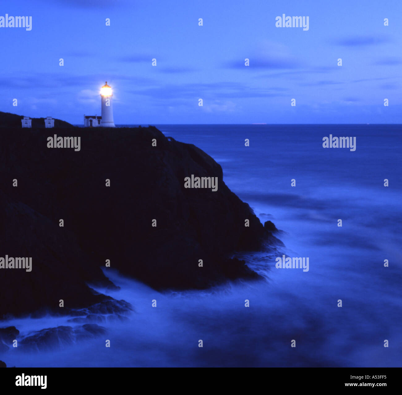 The pacific ocean at dusk accented by the beam of North Head Lighthouse ...