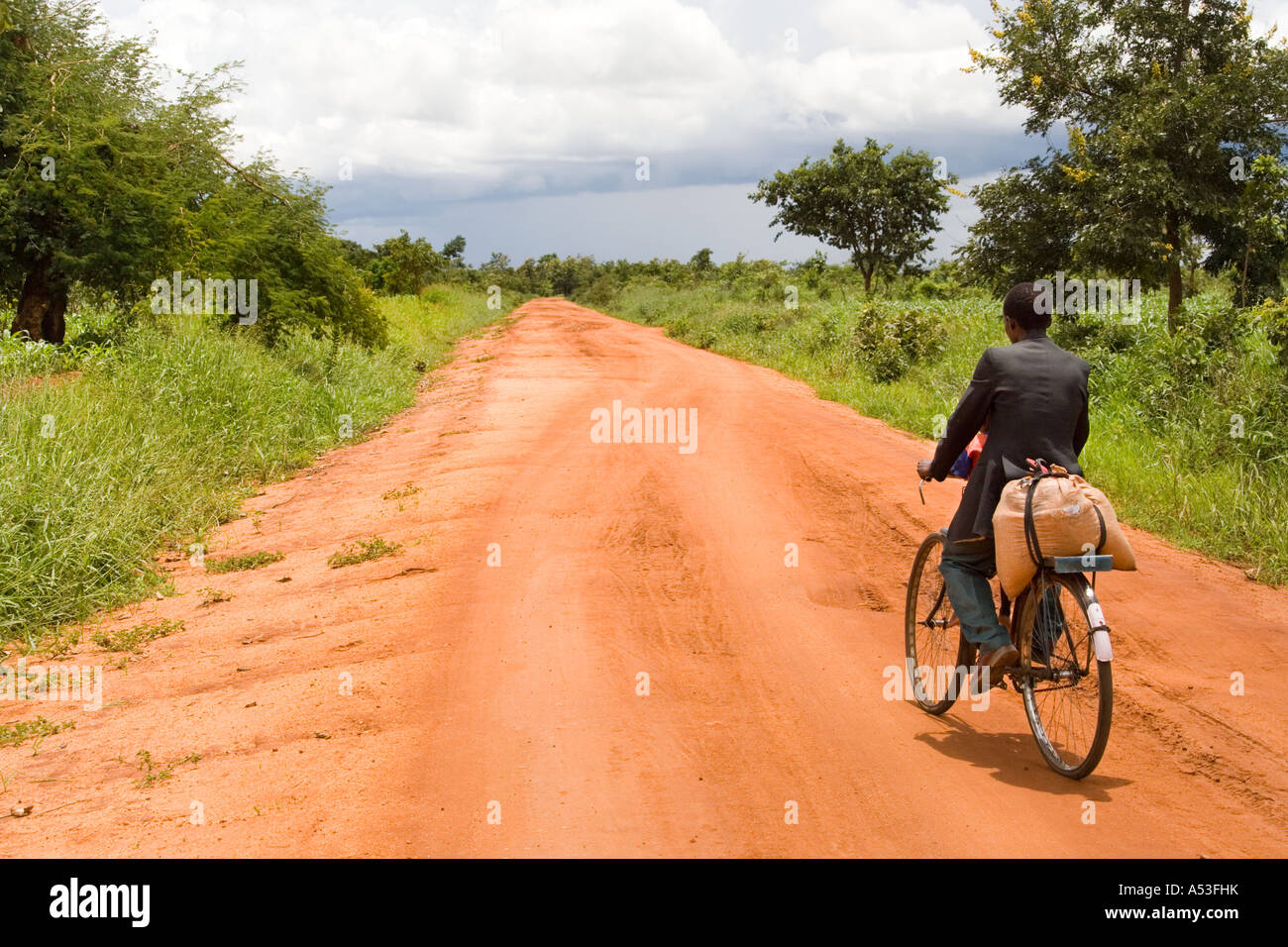 Man cycling along a typical dirt track road near Muzamanzi, Malawi, Africa Stock Photo