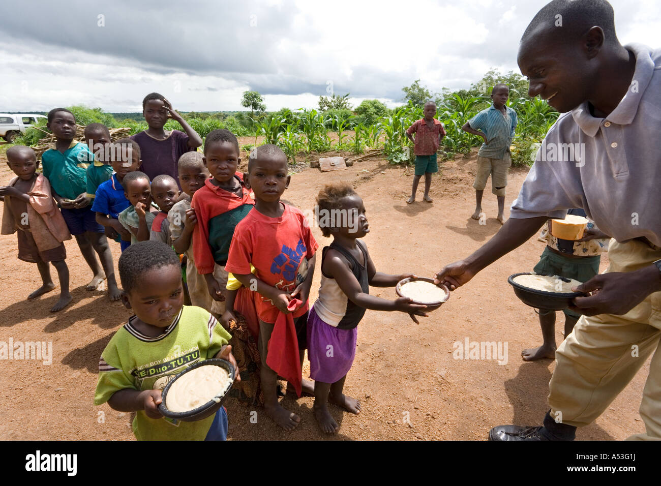 Serving phala to hungry children as part of the Joseph Project feeding programme in the village of Buli, Malawi, Africa Stock Photo