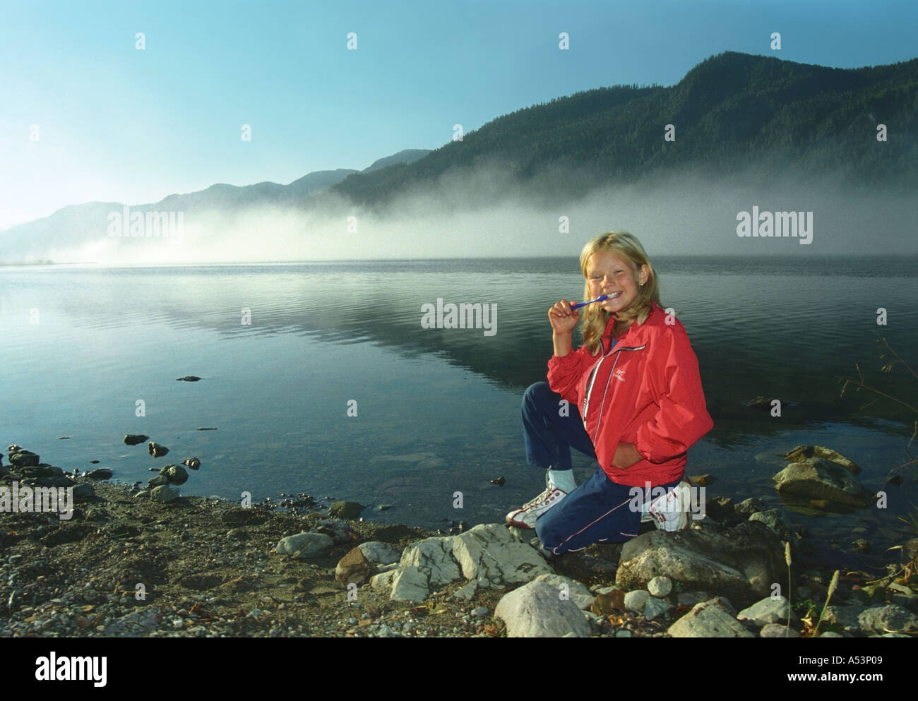 A girl is brushing teeth at the Teletskoye Lake coast Altai Siberia Russia Stock Photo