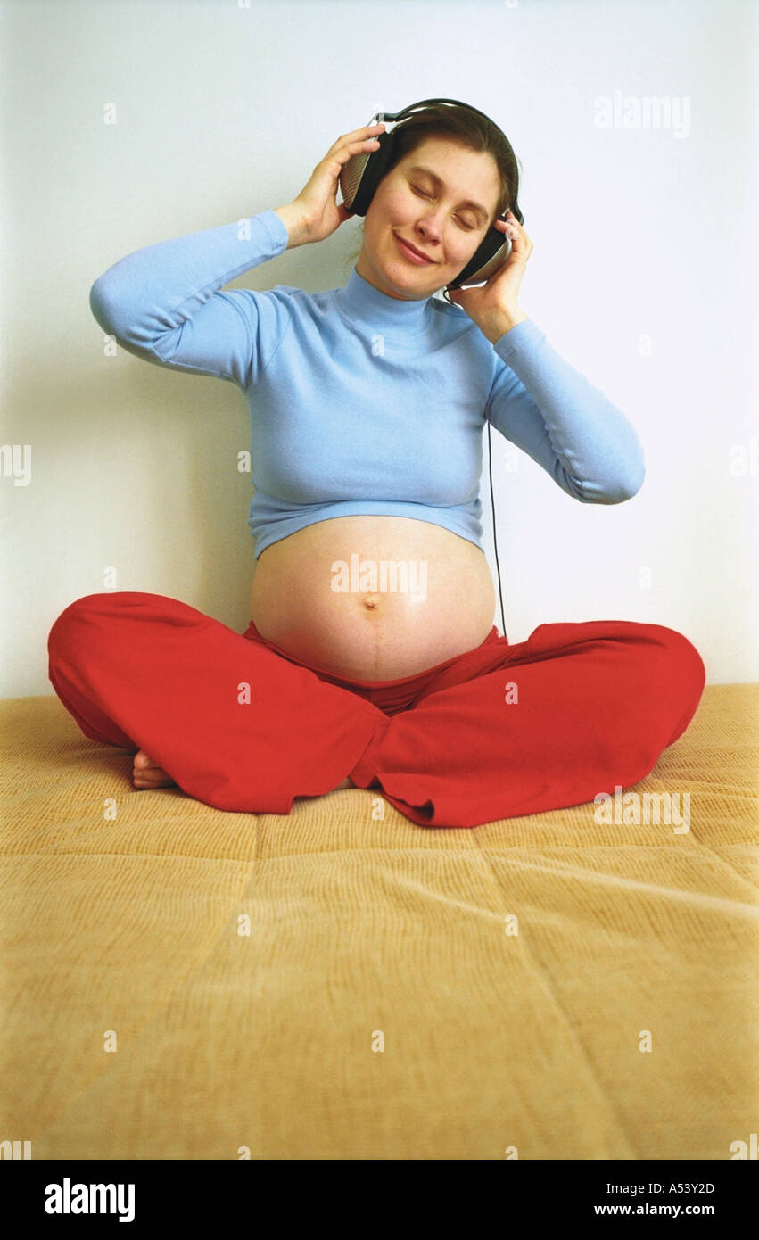 A pregnant woman listening music with headphones Stock Photo - Alamy