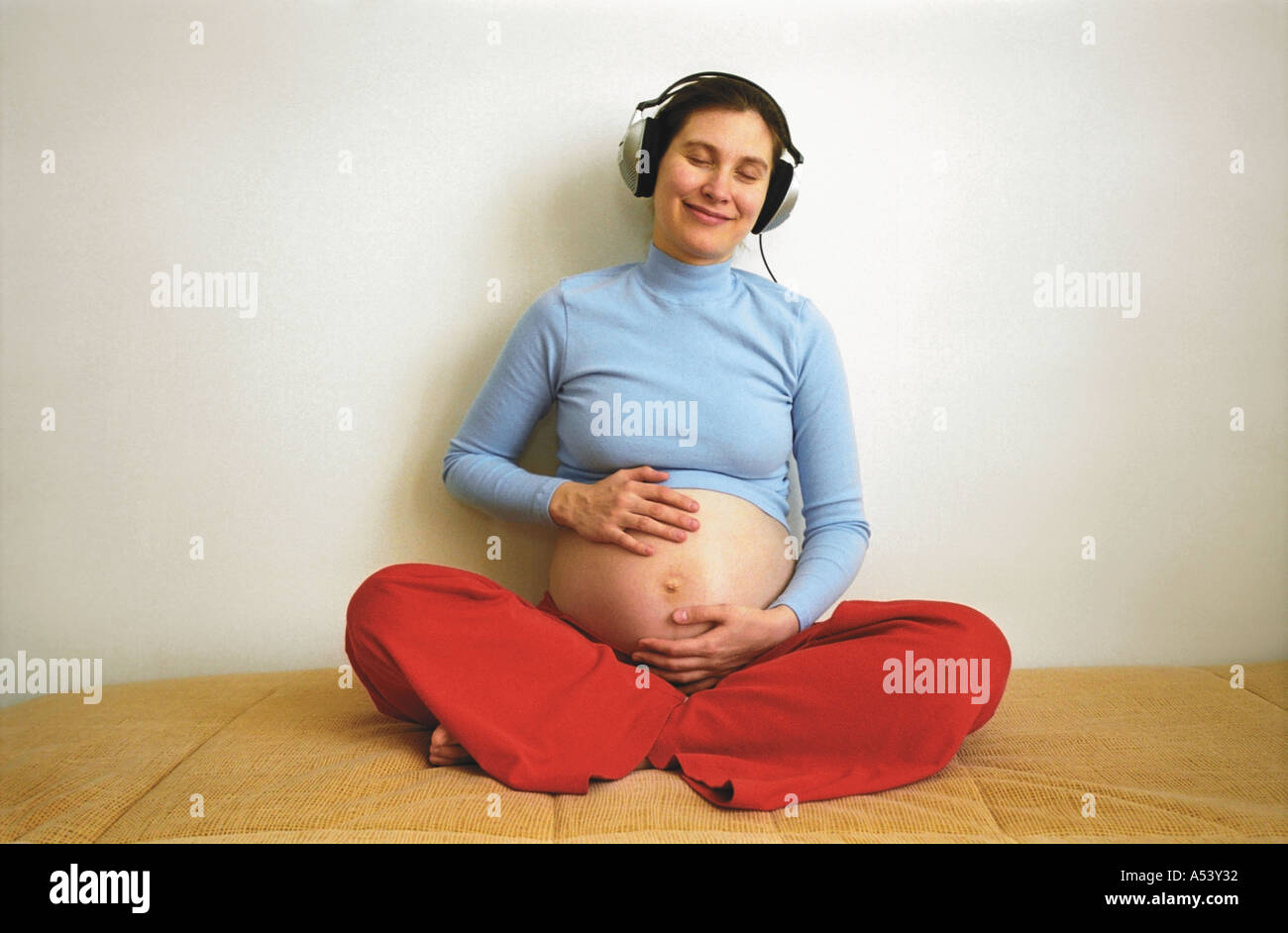 A pregnant woman listening music with headphones Stock Photo - Alamy