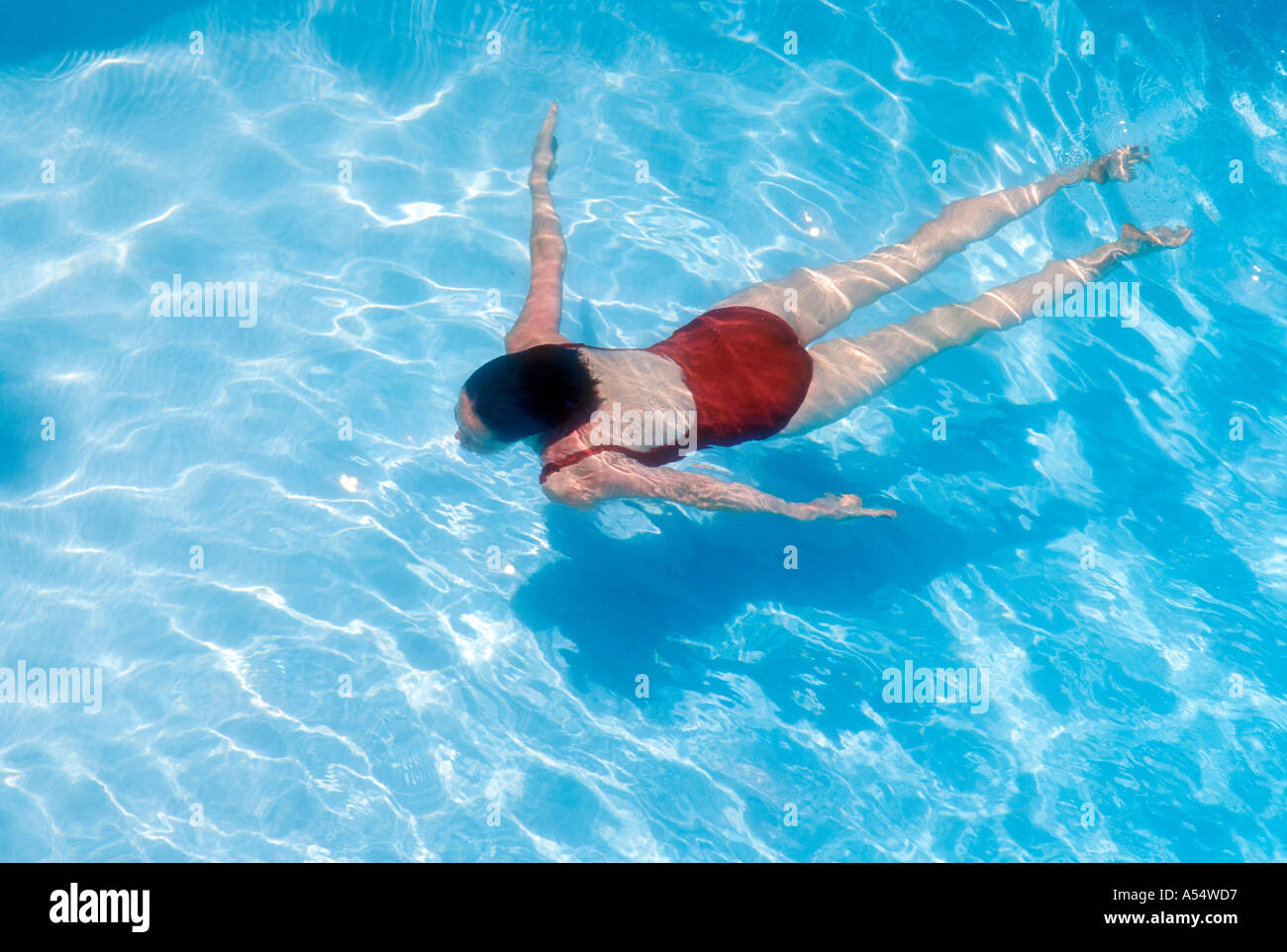 Woman swimming underwater in pool Model Released Photo Stock Photo