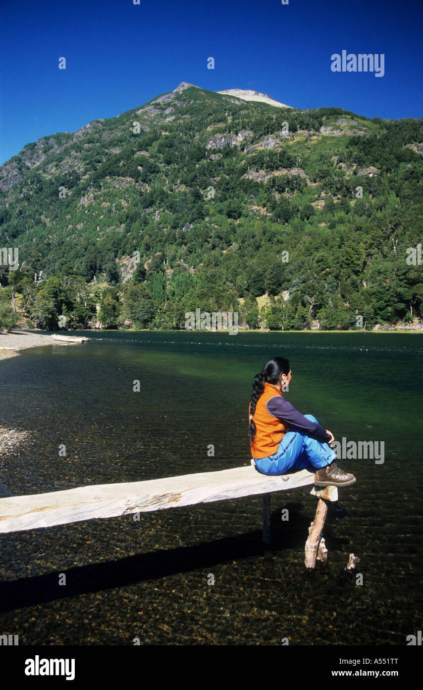 Latina girl sitting on rustic wooden jetty looking at view, Lake Paimun, Lanin National Park, Neuquen Province, Argentina Stock Photo
