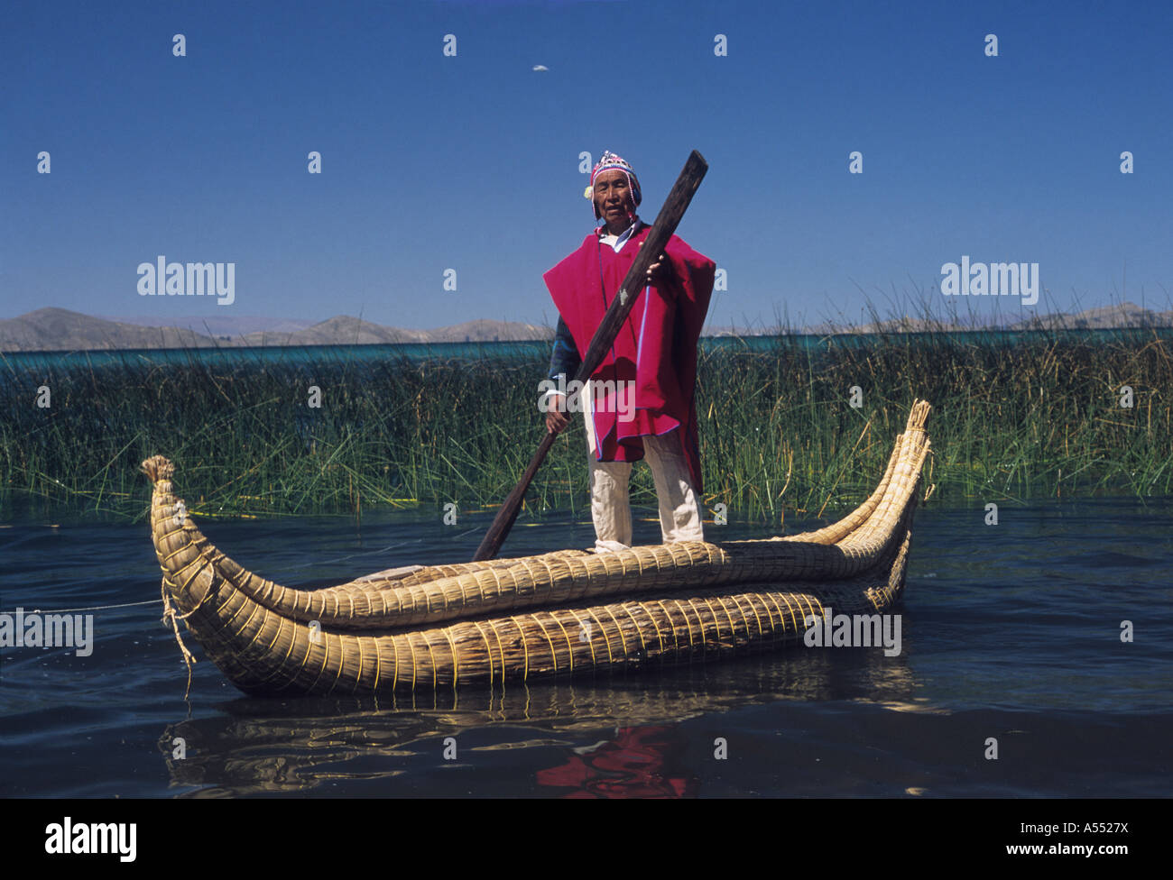 Paulino Esteban (a well known reed boat builder) standing on a totora reed boat wearing traditional dress, Lake Titicaca, Bolivia Stock Photo