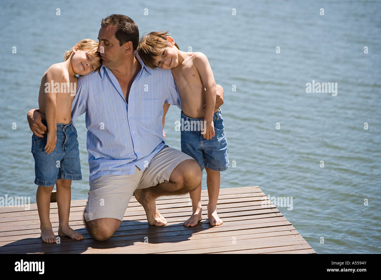 Father and sons on a wooden pier Stock Photo