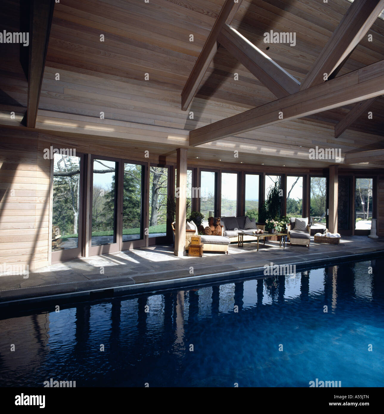 Large indoor swimming pool in country barn conversion with comfy sitting  area and view of garden through windows Stock Photo - Alamy