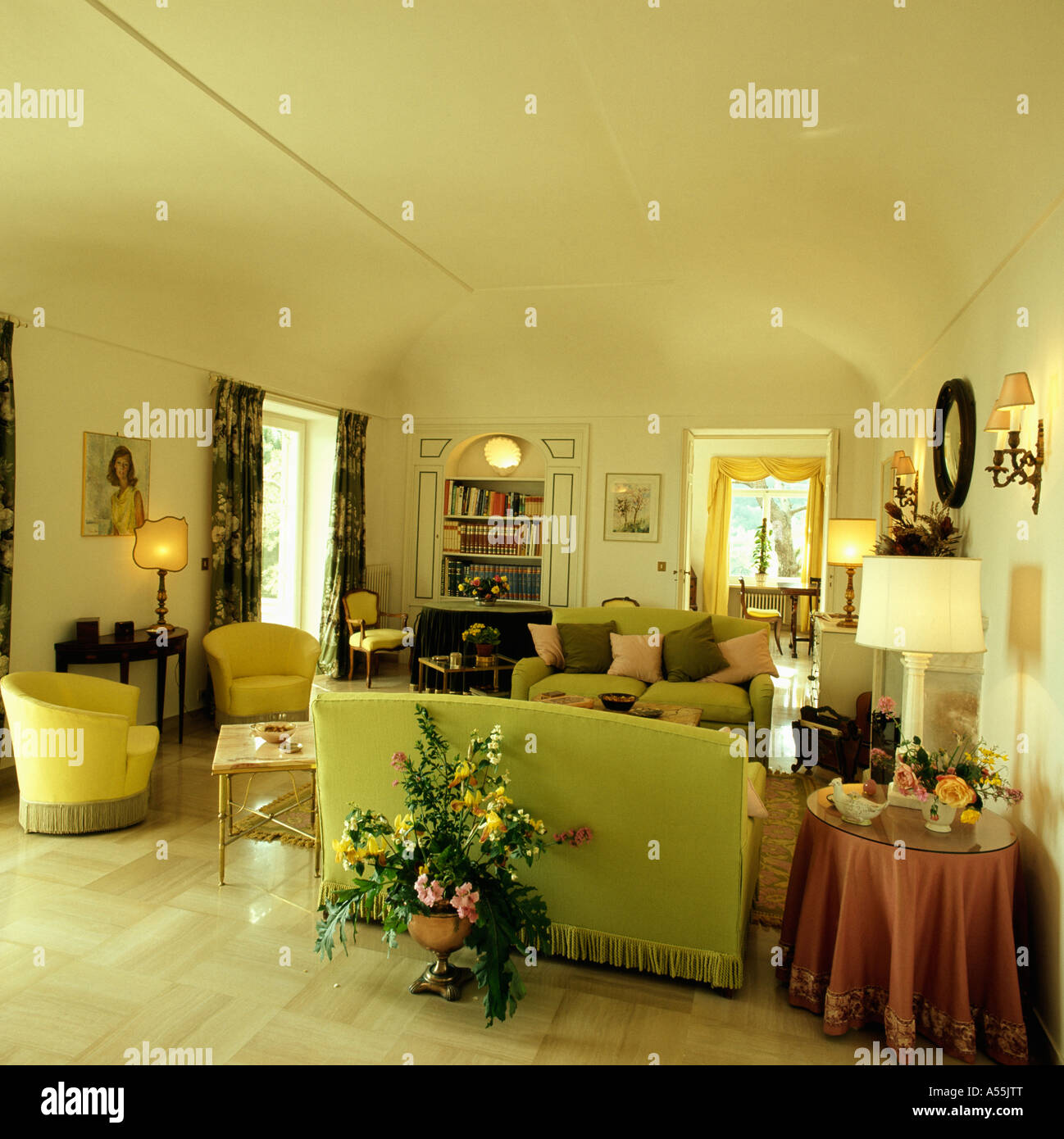 Large floral arrangement on floor behind pastel green sofa in country