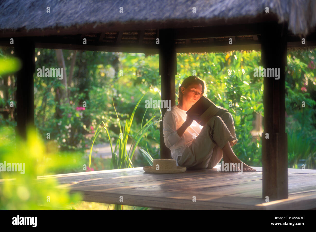 Woman reading in thatched bungalow on Gili Trawangan island Lombok Indonesia Model Released Stock Photo