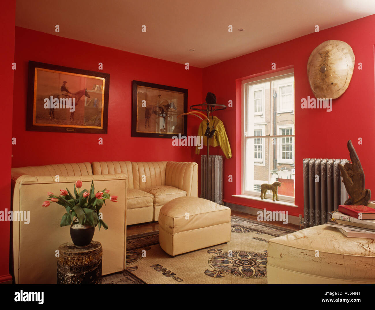 Red sittingroom with cream leather settees and stools Stock Photo Alamy