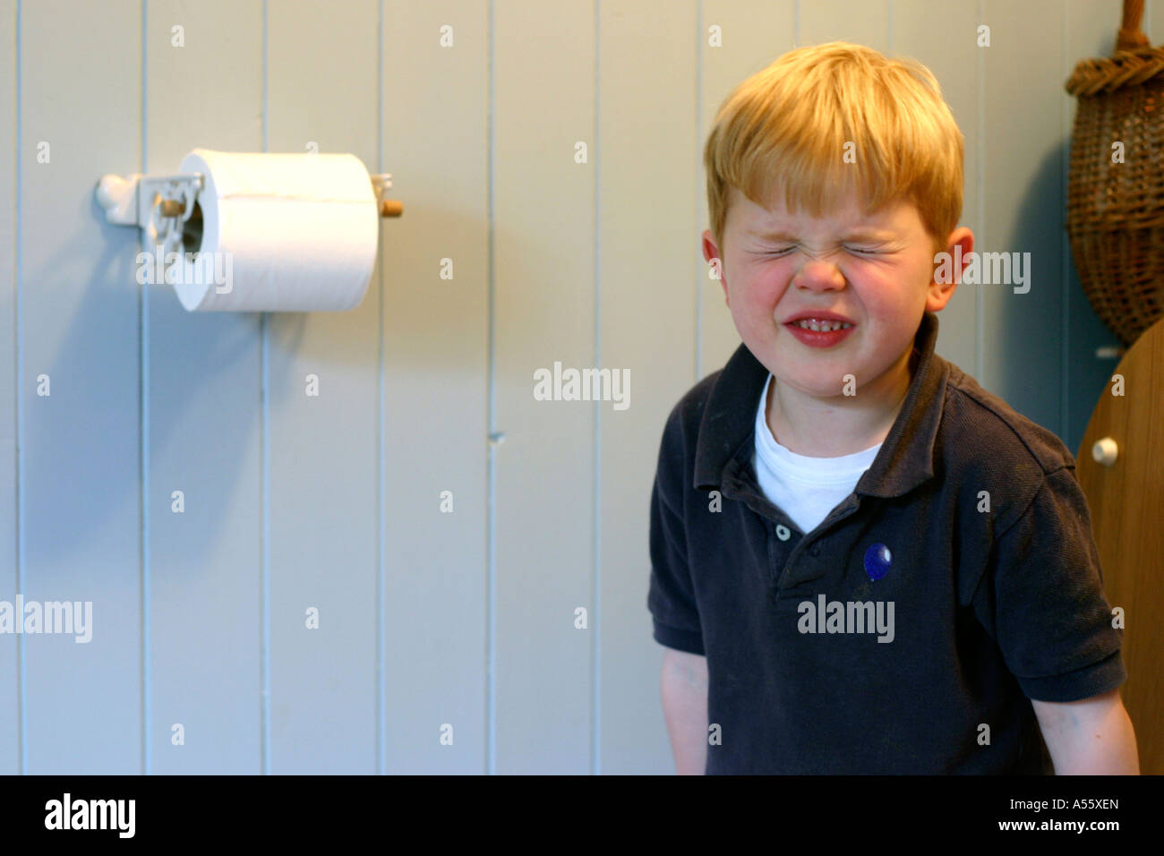 four year old boy pulling a face sitting on toilet Stock Photo