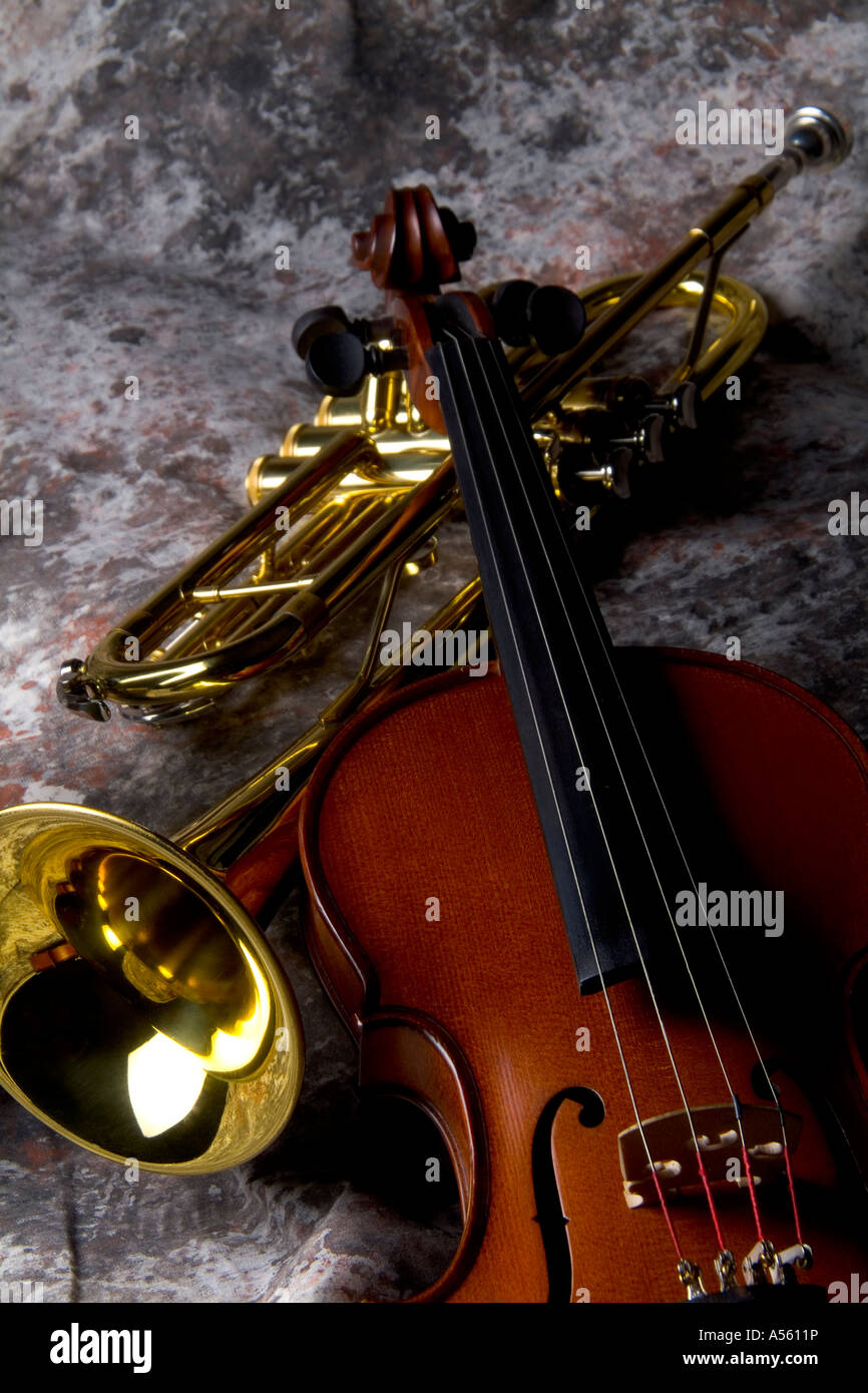 Violin resting on trumpet on mottled background Stock Photo