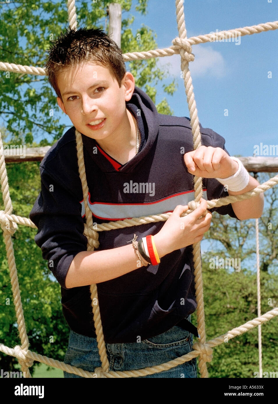 Teenage boy climbing a scramble net. Stock Photo