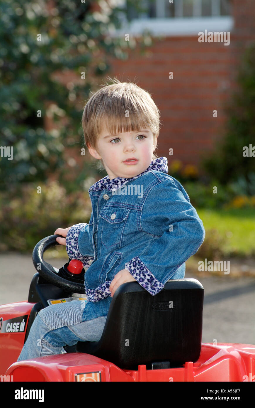 happy child kid play playing playful outside exercise on toy tractor pedal ride smile glee enjoy smiling Stock Photo