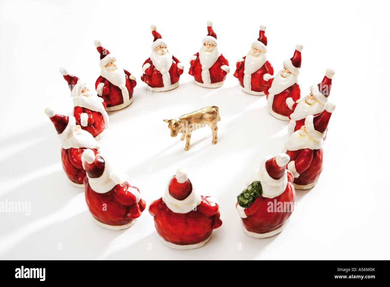 Golden calf, surrounded by Santa Clauses Stock Photo
