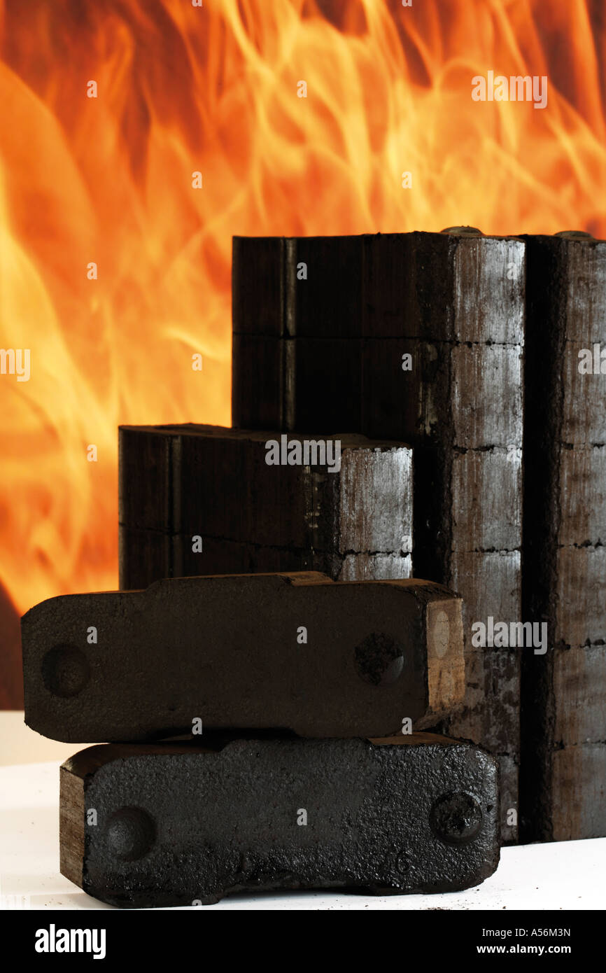 Piled briquettes, fire in background Stock Photo