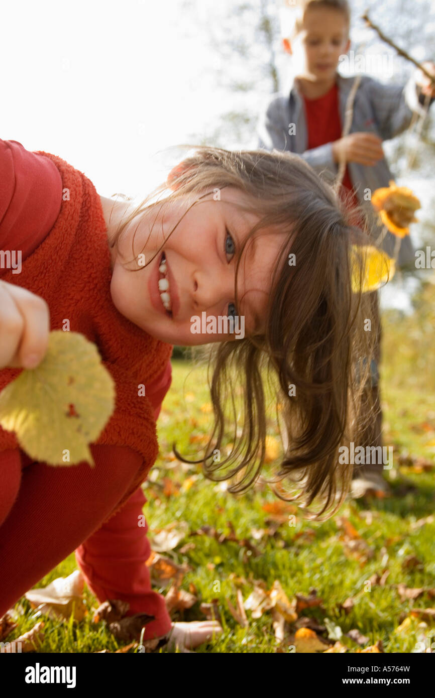 Girl (6-9) holding leaf boy (10-13) in background Stock Photo - Alamy