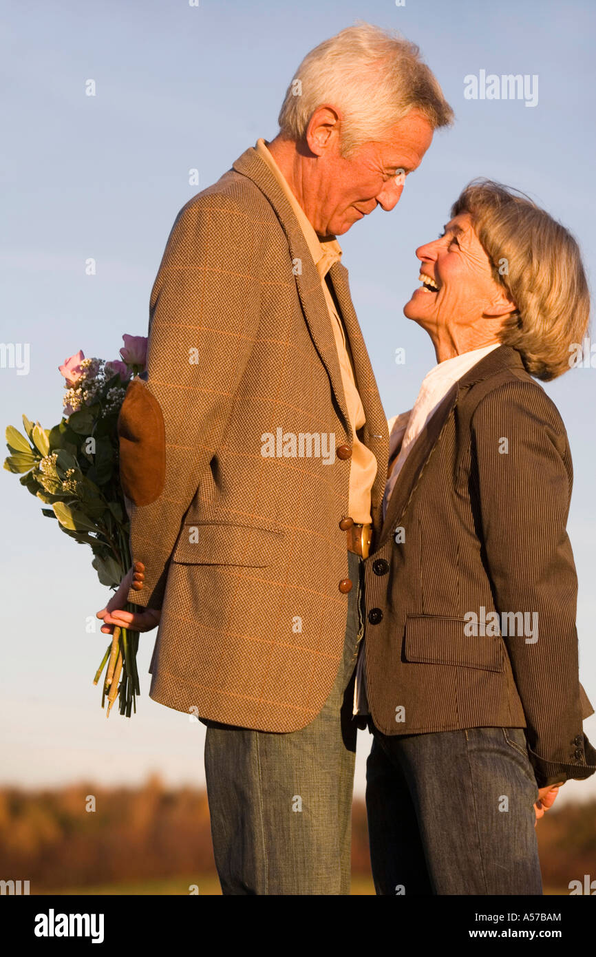 Senior couple, man hiding bouquet, side view Stock Photo