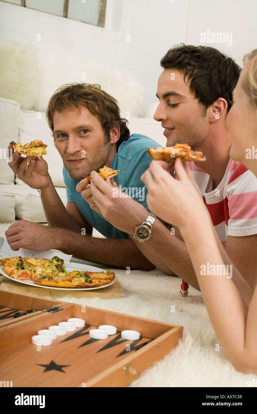 Three young people lying on floor, eating pizza Stock Photo Alamy