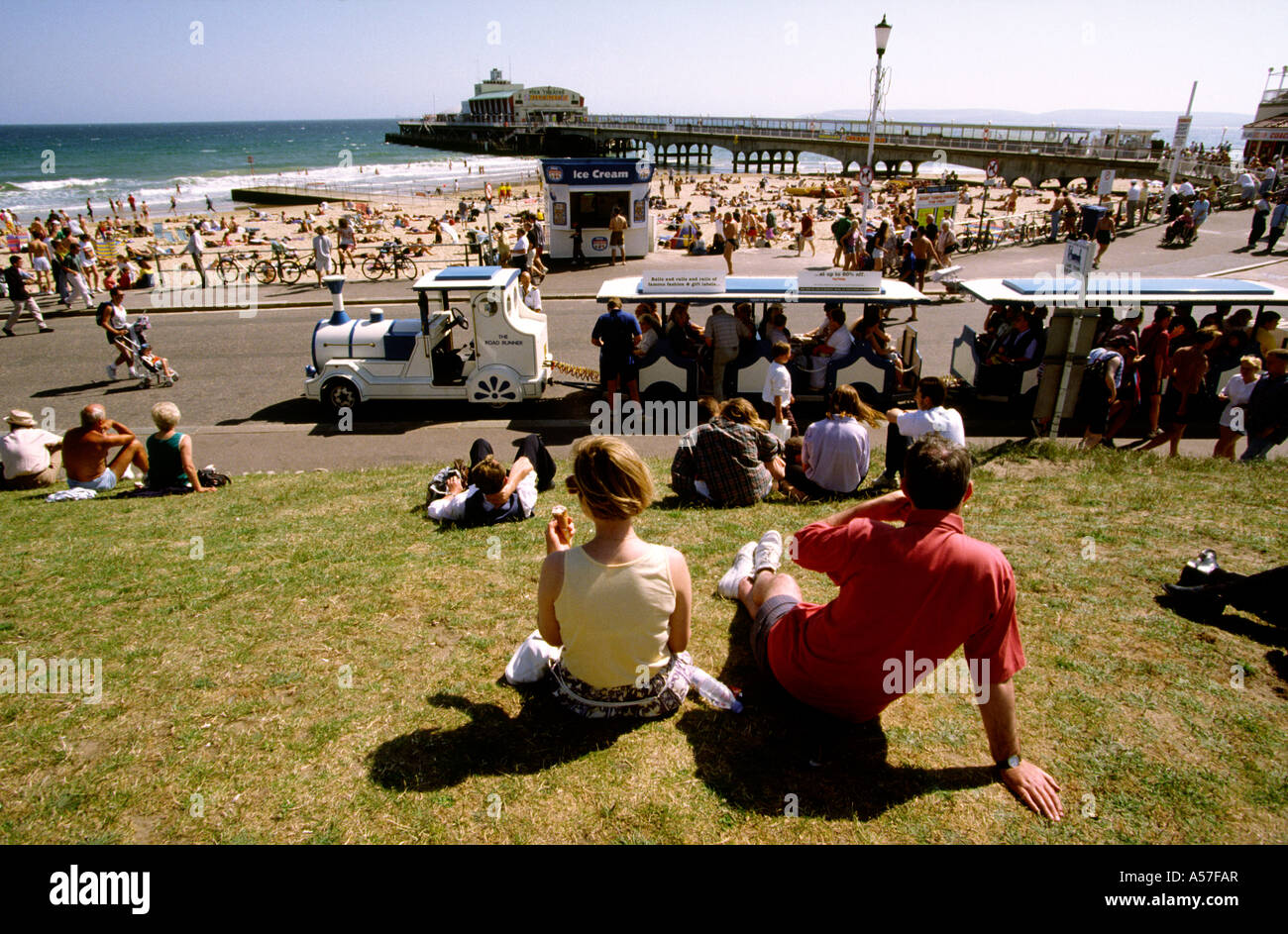 UK Dorset Bournemouth promenade land train in summer behind crowded beach Stock Photo