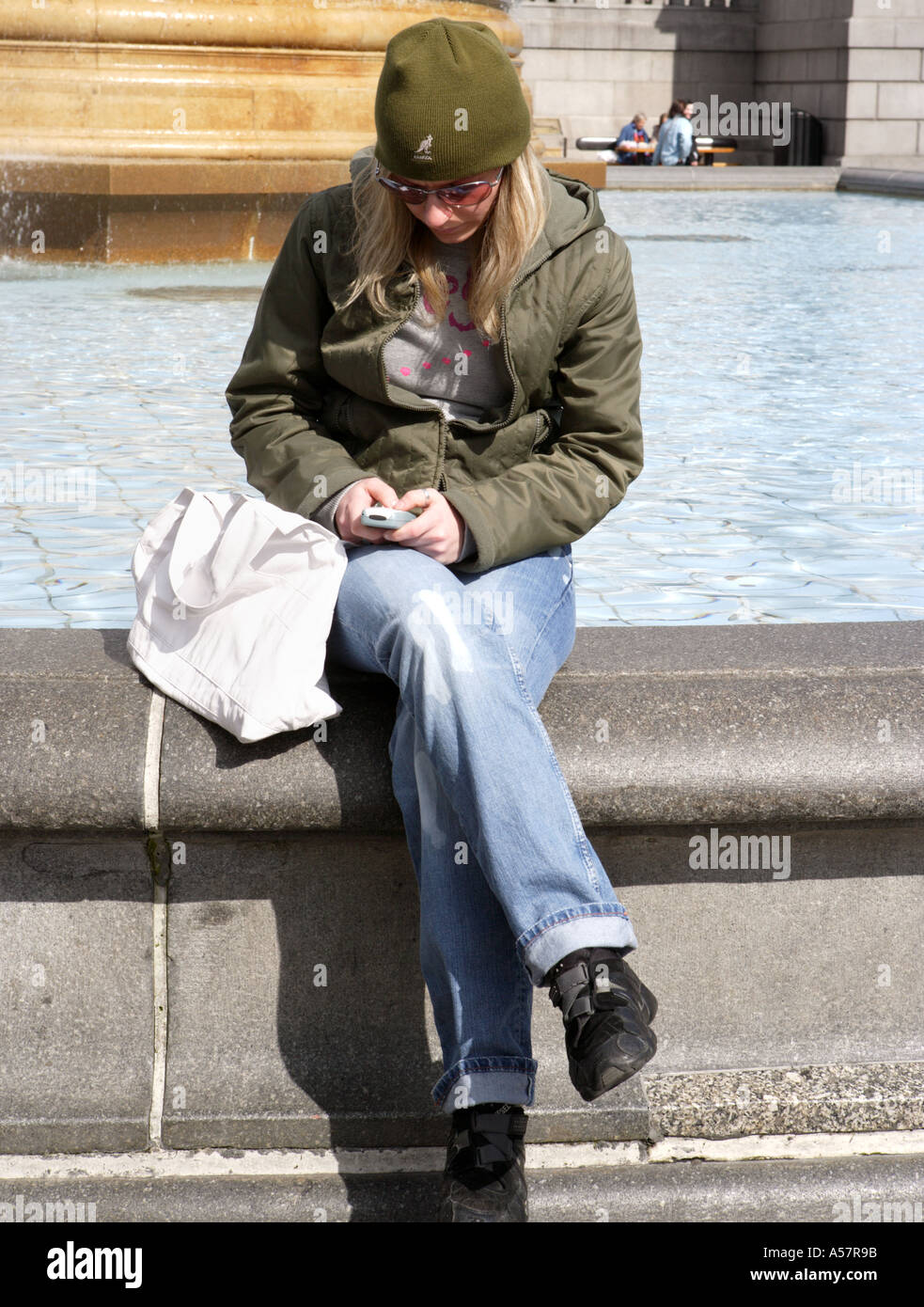 Woman texting on mobile phone in Trafalgar Square London England Stock Photo