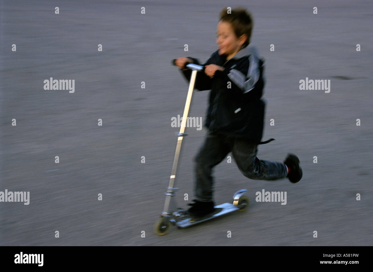 Young boy speeding on a kick scooter. Stock Photo