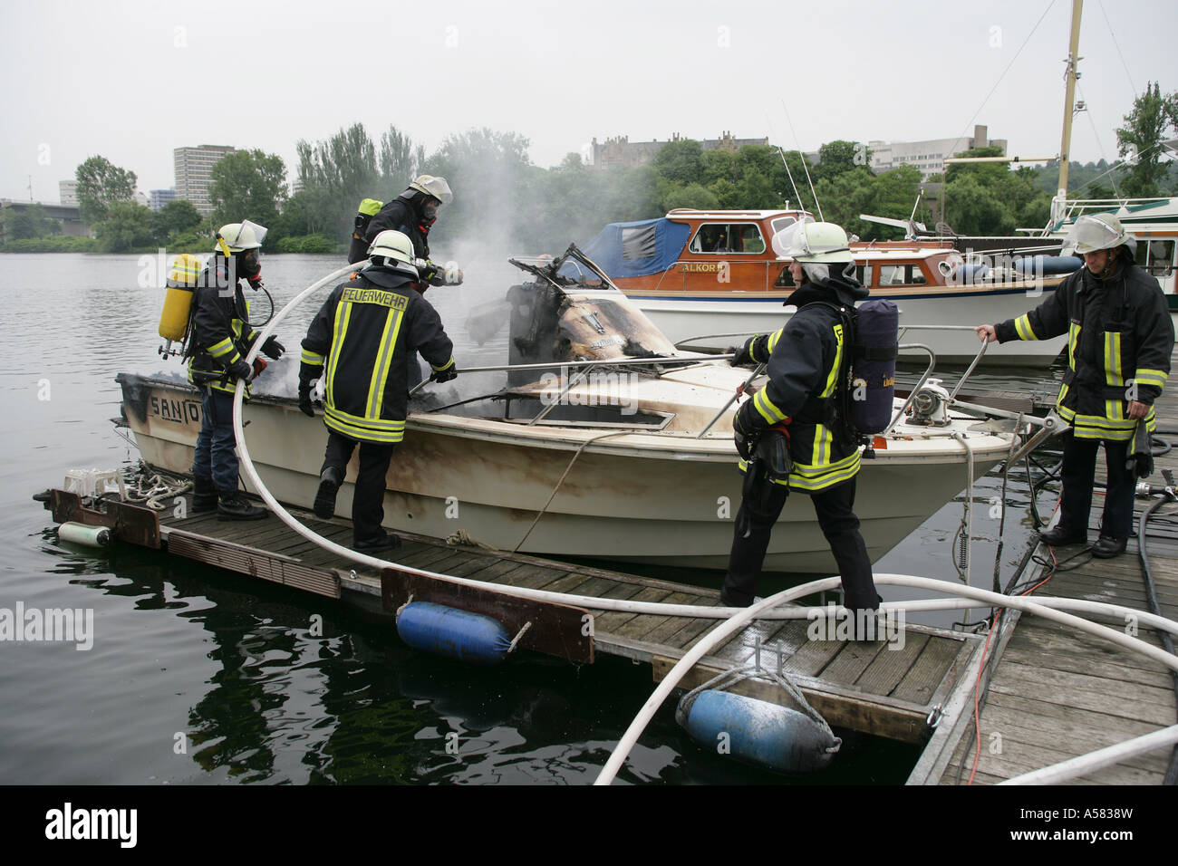 Firefighters are extinguishing the fire of a burning motor boat Stock Photo