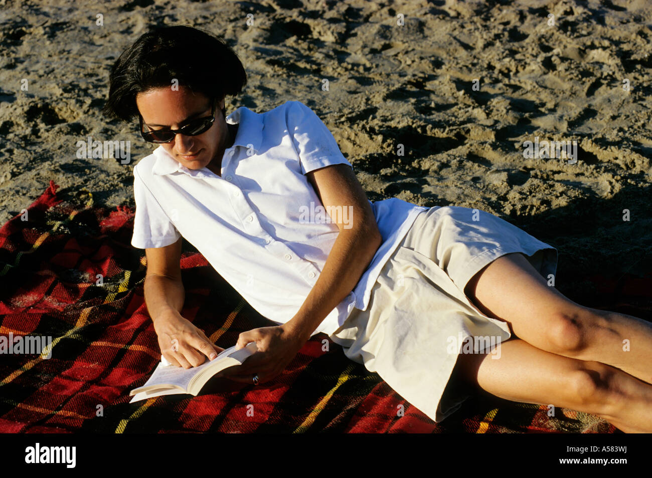 Woman lying on the beach reading a novel, Camargue, France. Stock Photo