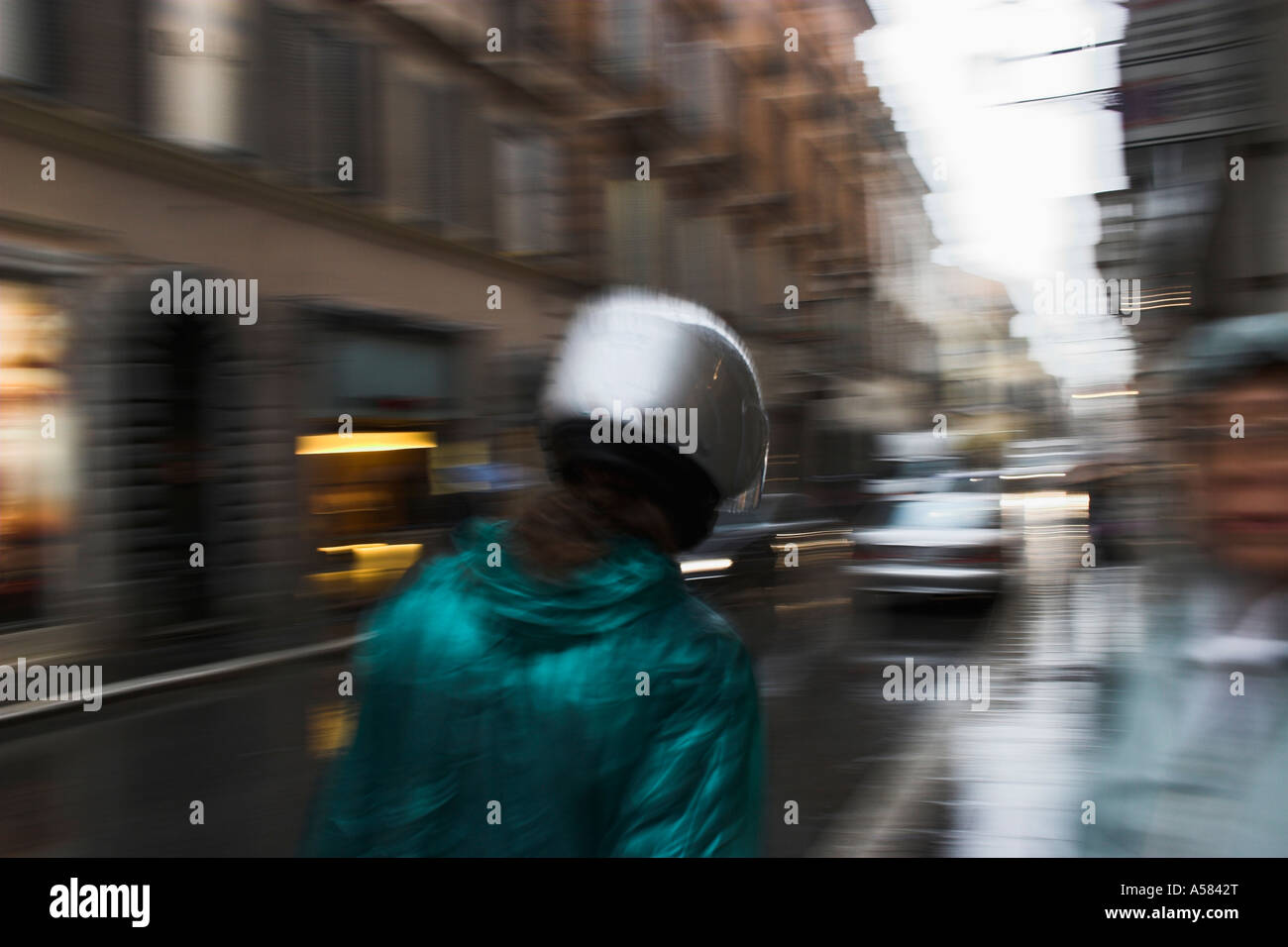 Young woman with helmet and rain-jacket, rainy weather, Rome, Italy Stock Photo