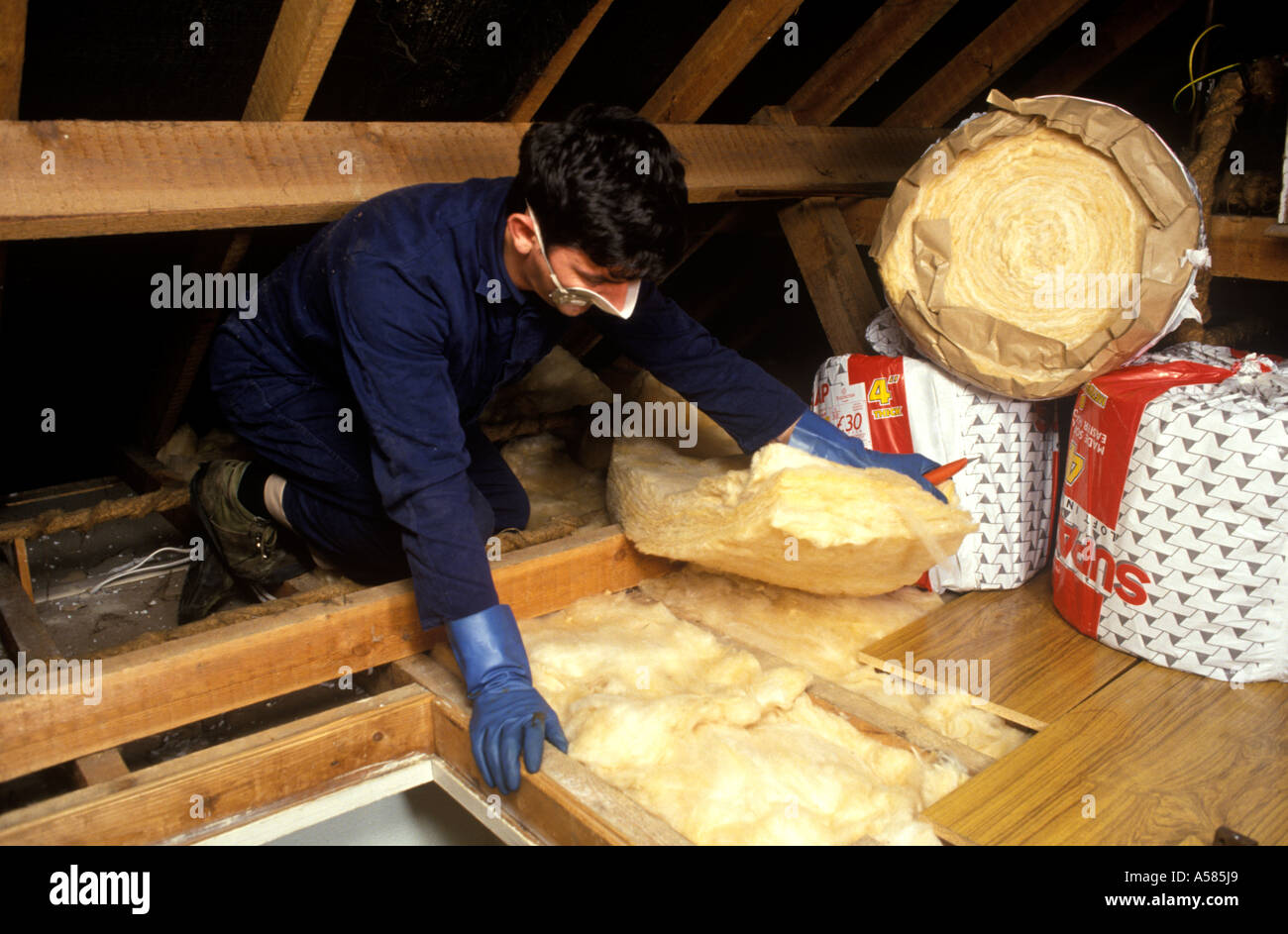 man putting down insulation in loft Stock Photo