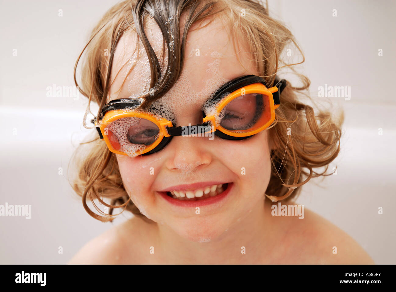 Little girl wearing goggles sitting in a bath tub Stock Photo Alamy