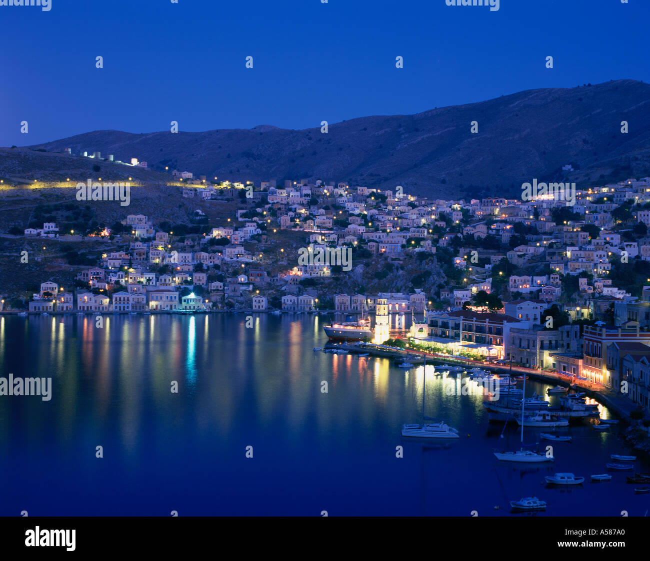 Greek town of Symi on hillside overlooking harbor and boats Nighttime