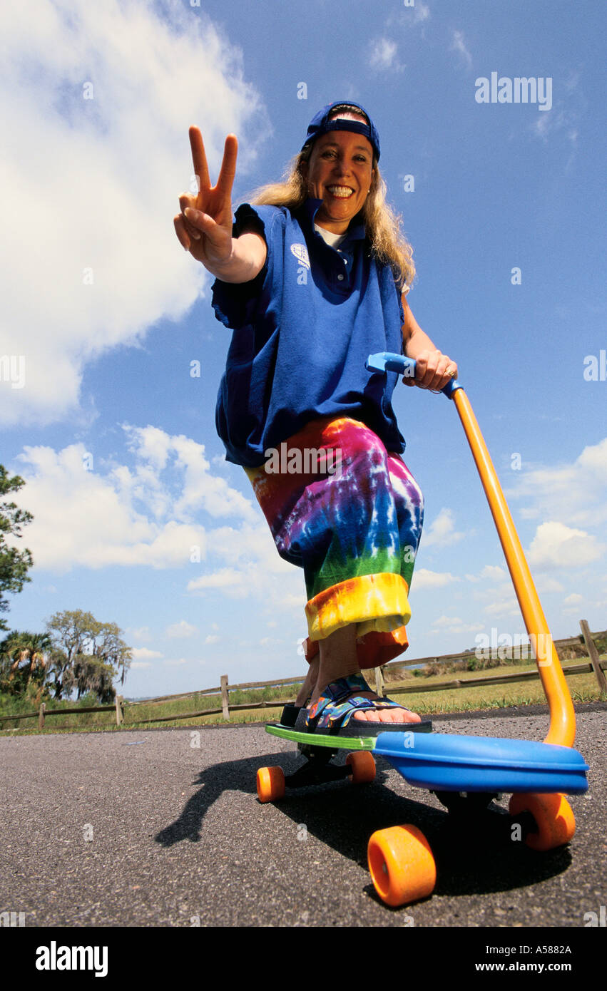 Young hippie woman wearing sandals giving a peace sign while riding her  hybrid scooter skateboard Stock Photo - Alamy