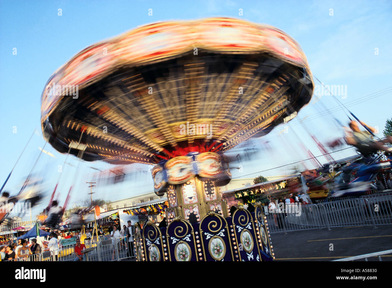 Spinning carnival ride along midway Blurred riders swinging from