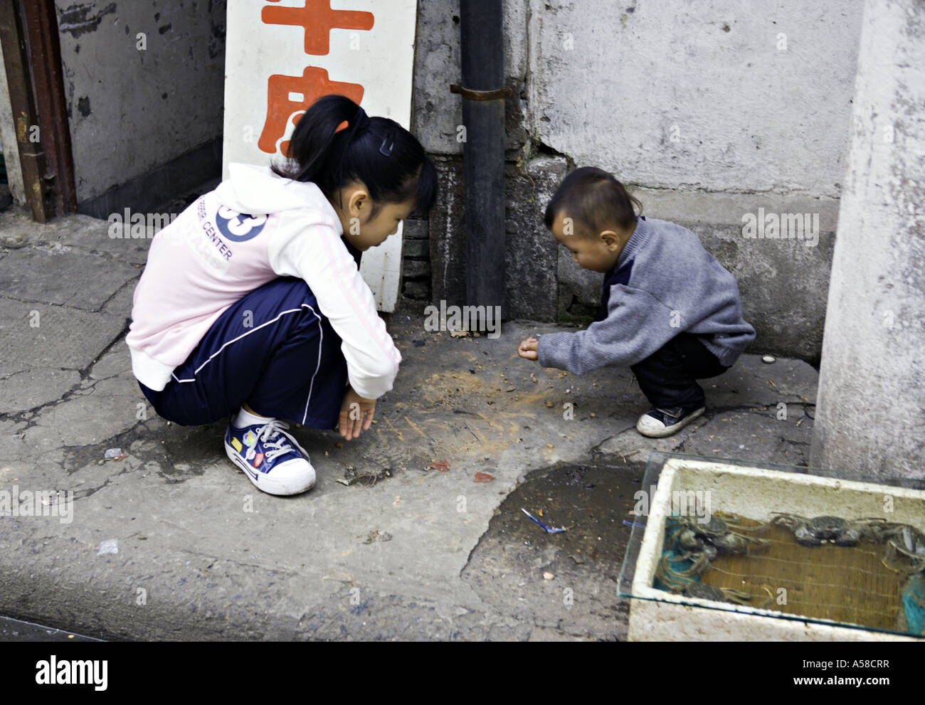 CHINA SHANGHAI Chinese children squat on the sidewalk outside their