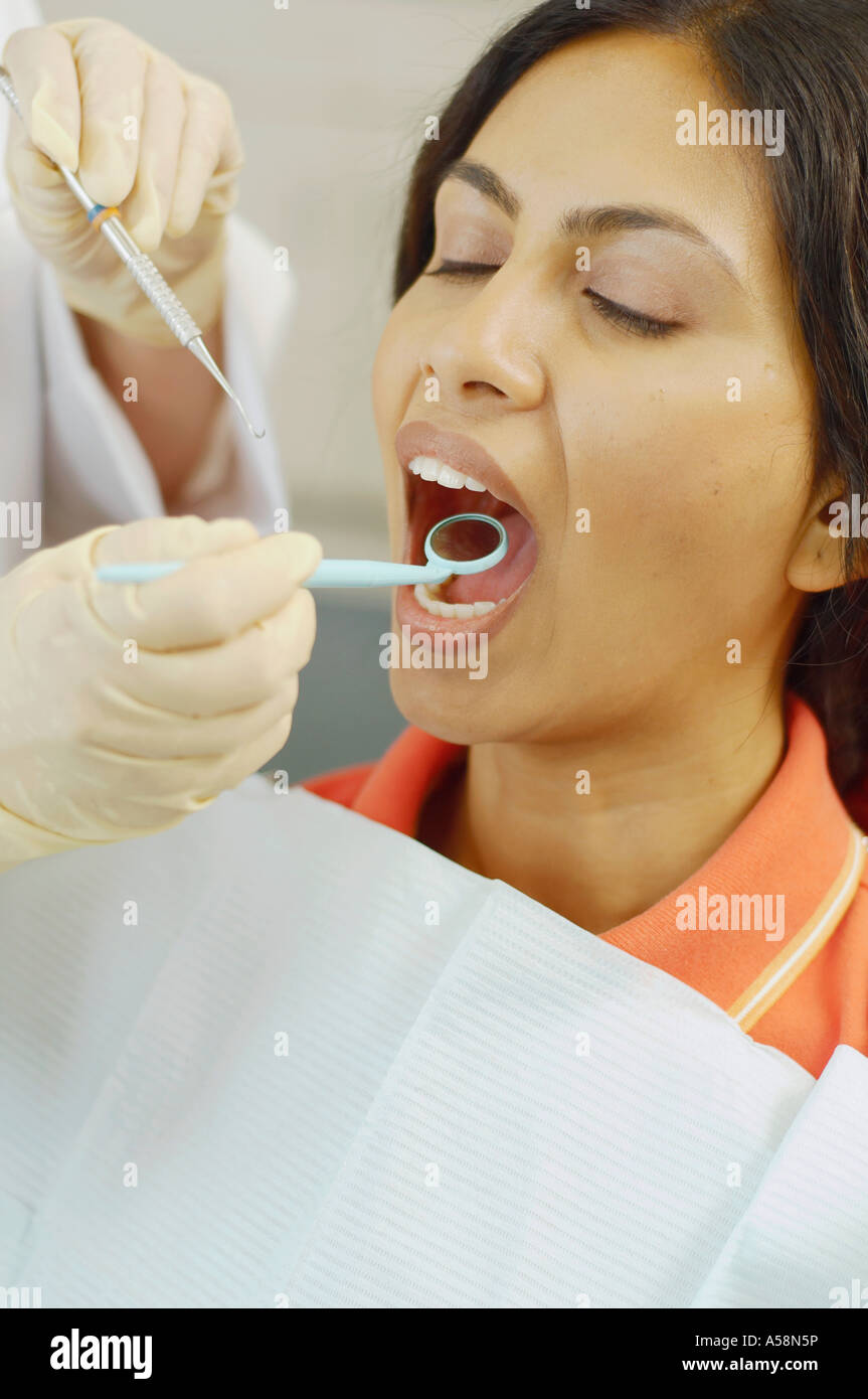 Dentist holding dental mirror in female patient s mouth Stock Photo