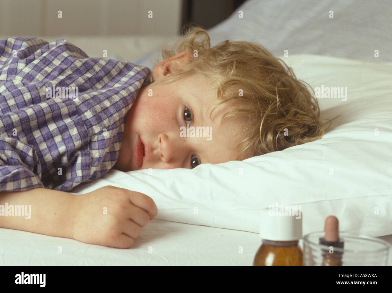 child lying in bed looking ill Stock Photo
