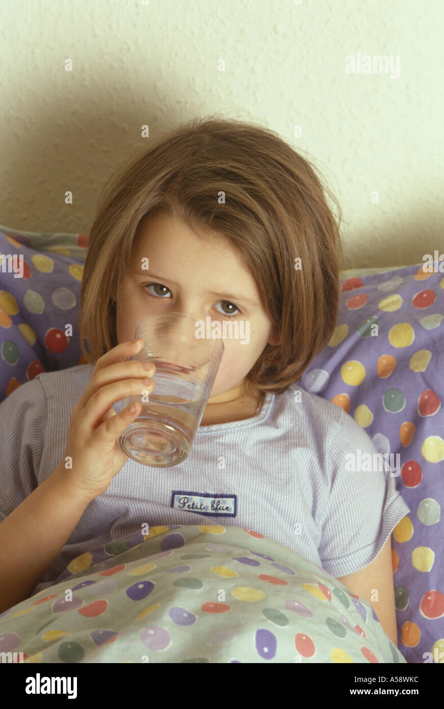 sick child in bed drinking water Stock Photo