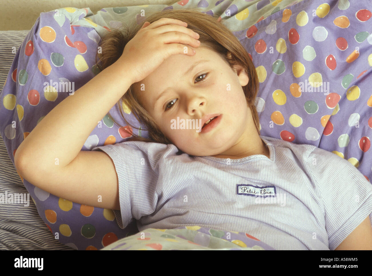 sick child in bed feeling feverish Stock Photo