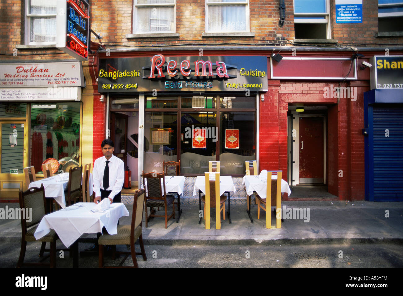 England, London, East End, Waiter Setting Tables in Brick Lane Stock Photo