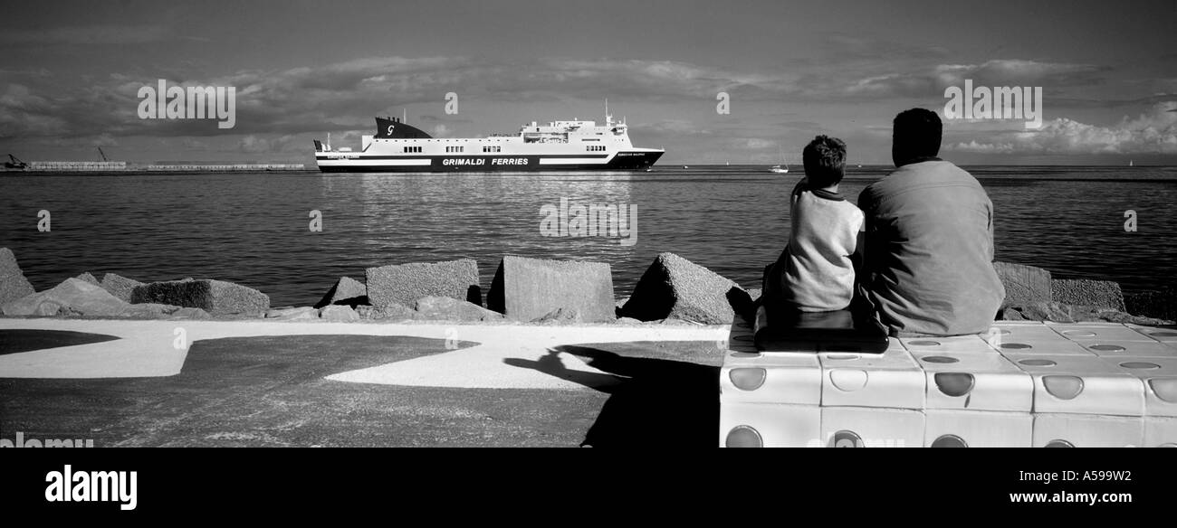 Father and son watching a ferry boat leaving the port Palermo Sicily Italy Stock Photo